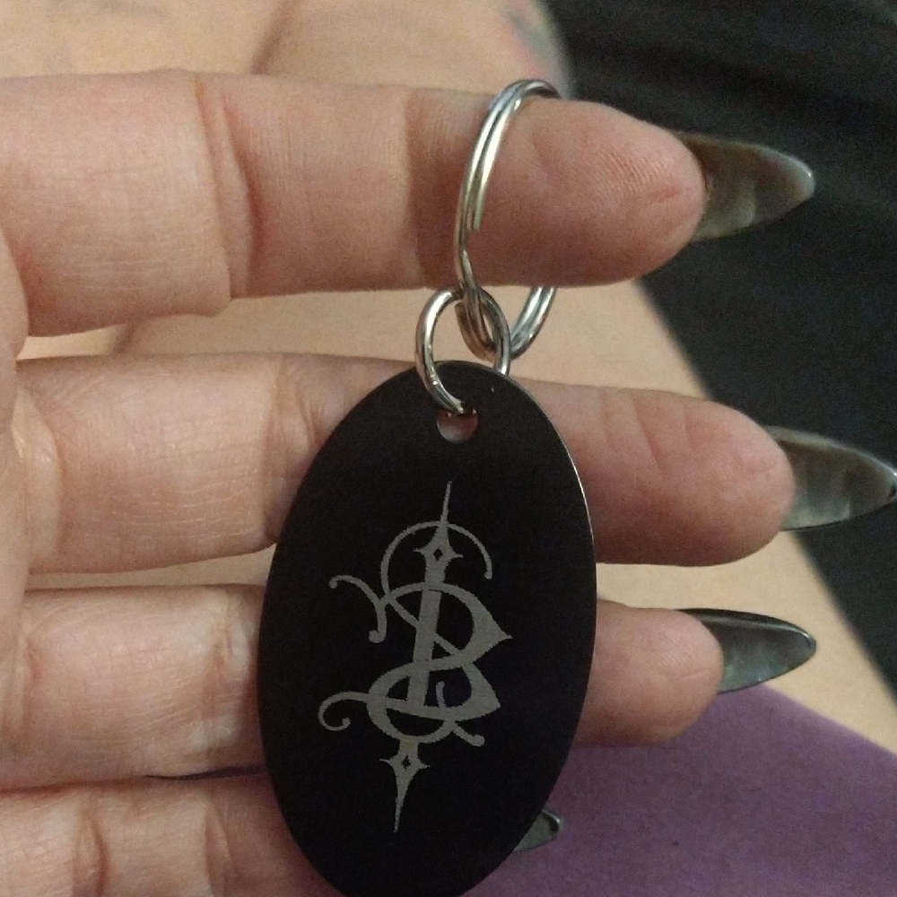 Black Oval Keychain With Silver Skinny Puppy Design